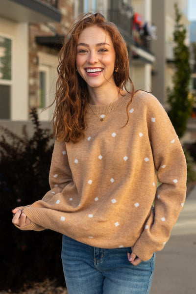 White polka dots on a camel sweater with long sleeves