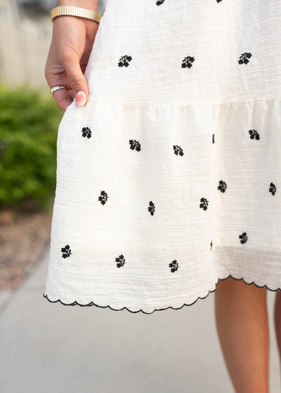 Close up of the black embroidered pattern and ivory fabric on the ivory embroidered floral dress