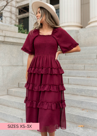 Front view of a burgundy tiered dress with square neck