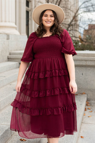 Front view of a plus size burgundy dress with a smocked bodice 