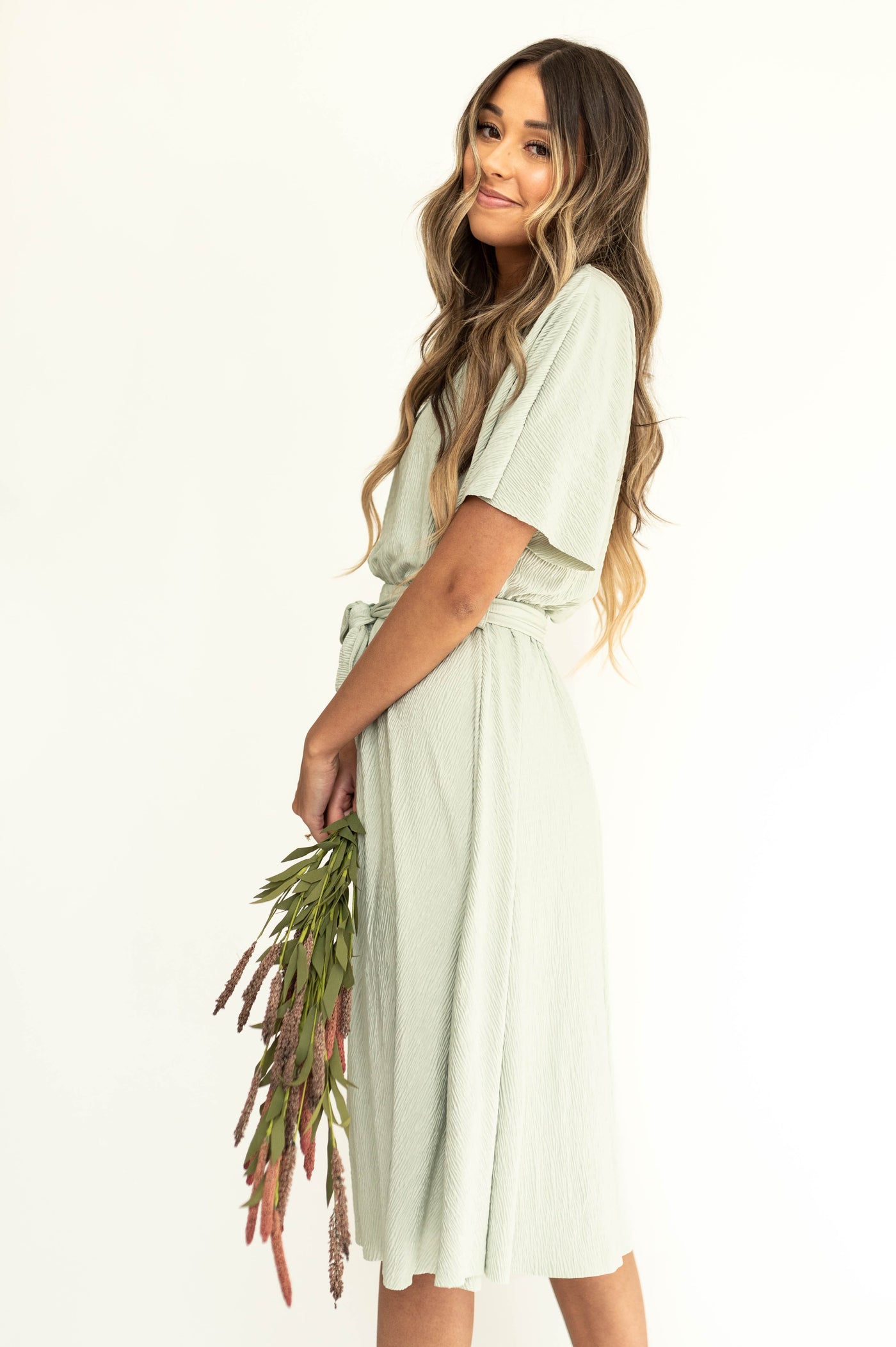 Side view of a short sleeve sage dress that ties at the waist