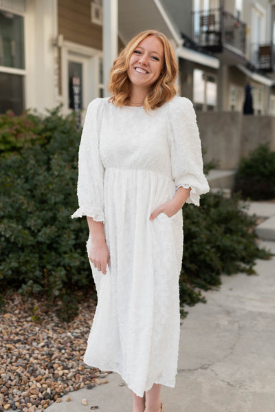 Front view of a white floral dress with a high waist and 3/4 sleeves