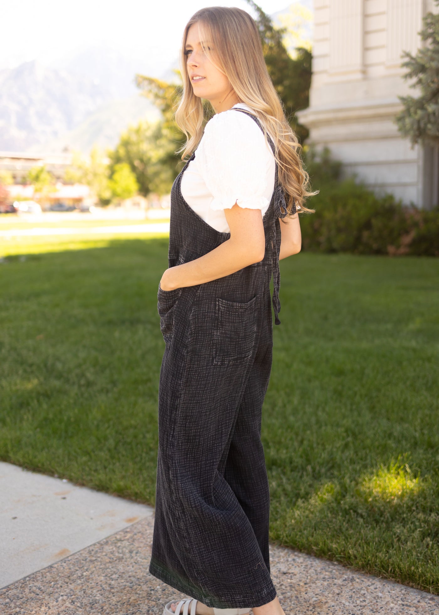 Side view of a black jumpsuit with pockets