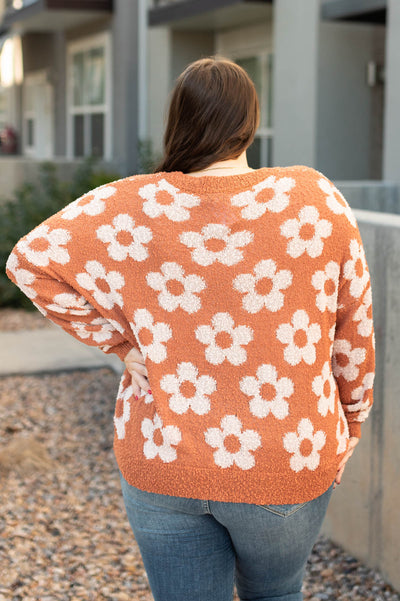Back view of a plus size caramel sweater with daisies