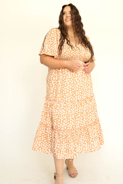 Plus size short sleeve apricot dress with white flowers and a V-neck.