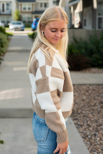 Side view of a ivory sweater with a checkered pattern