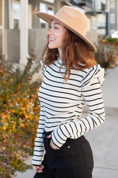 Side view of a cream stripe bodysuit with ruffles on the shoulders