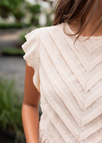 Close up of the pleats on the bodice of the beige swiss dot dress