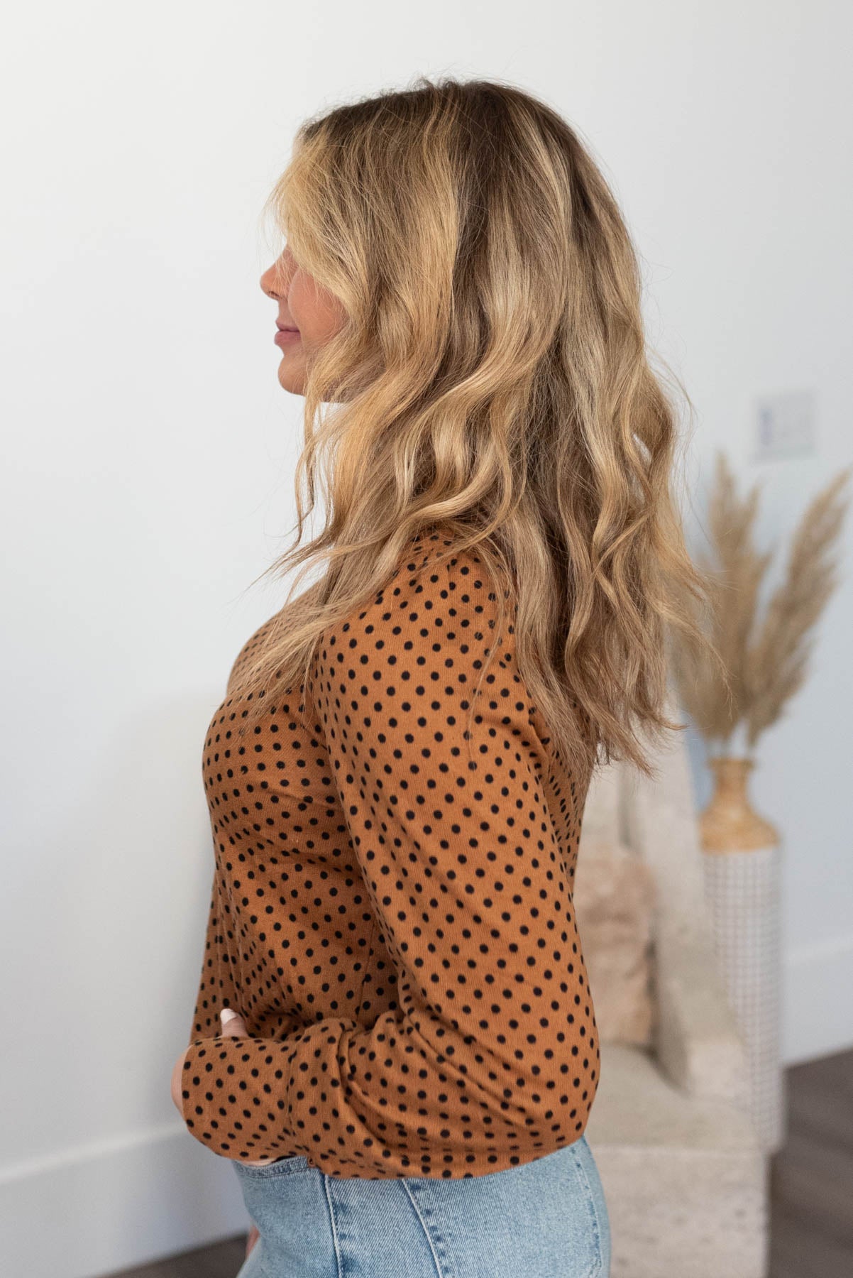 Side view of a brown turtleneck with long sleeves and polka dots