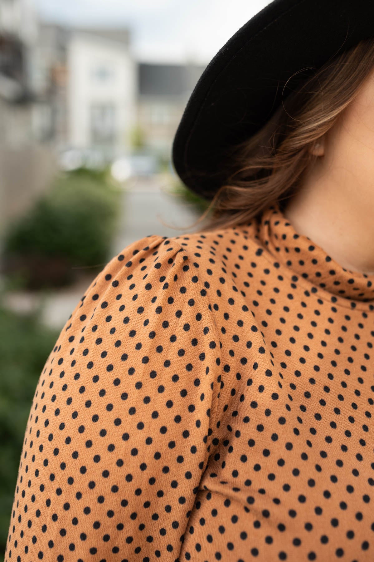 Sleeve view of a plus size brown turtleneck with polka dots