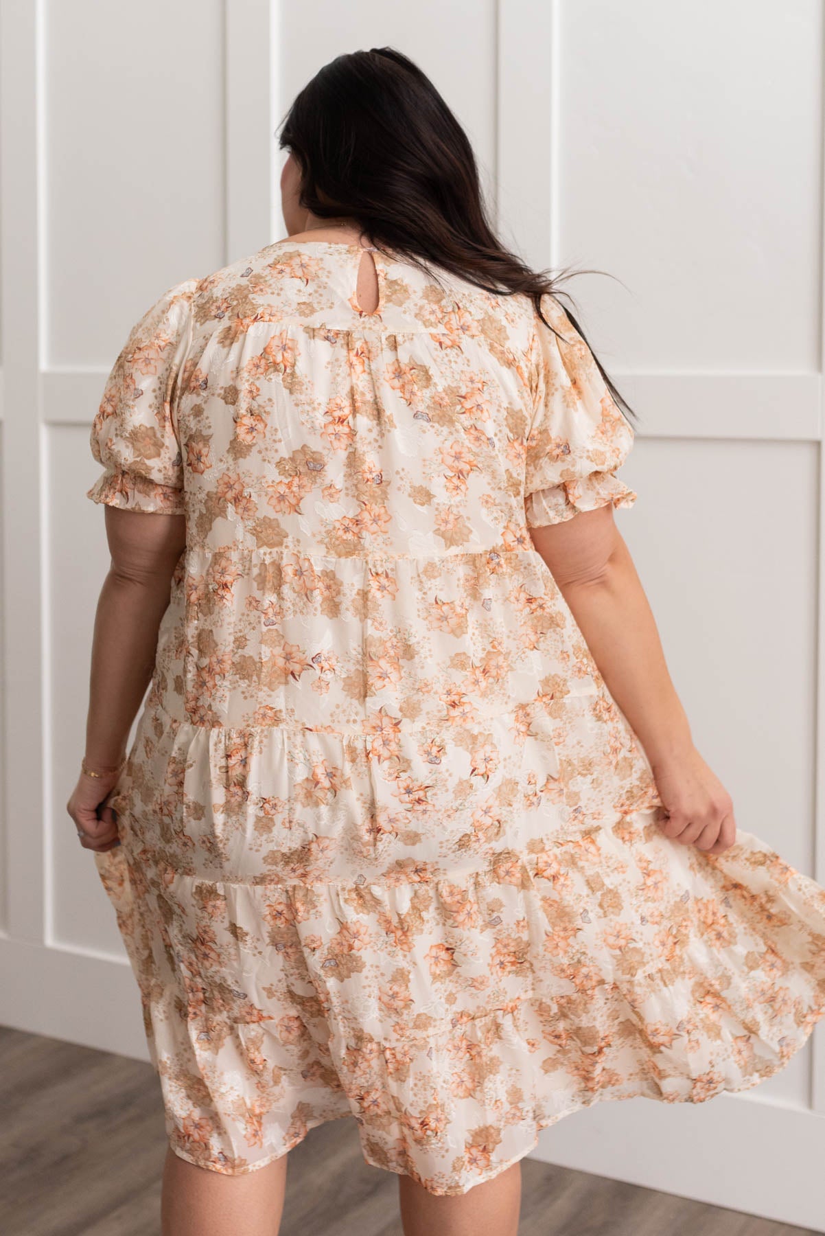 Back view of a plus size peach floral tiered dress