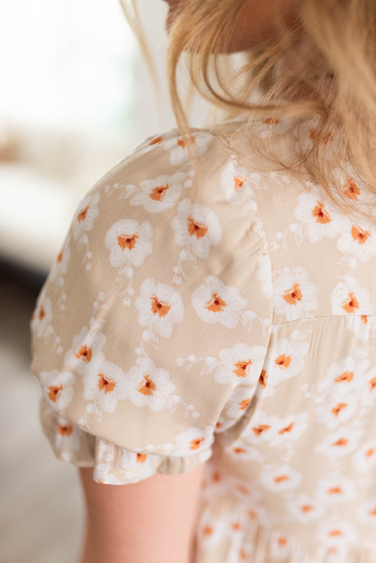Close up of the sleeve and fabric pattern on the beige floral tiered dress