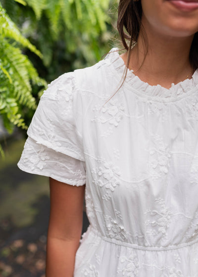 White floral embroidered dress with ruffle at the neck and double cuff