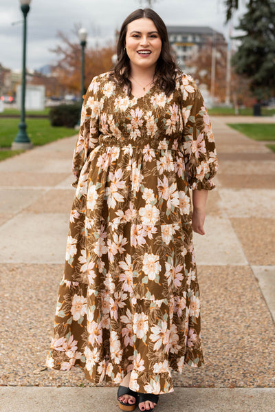 Front view of a v-neck plus size brown floral dress with tiered skirt and pocket