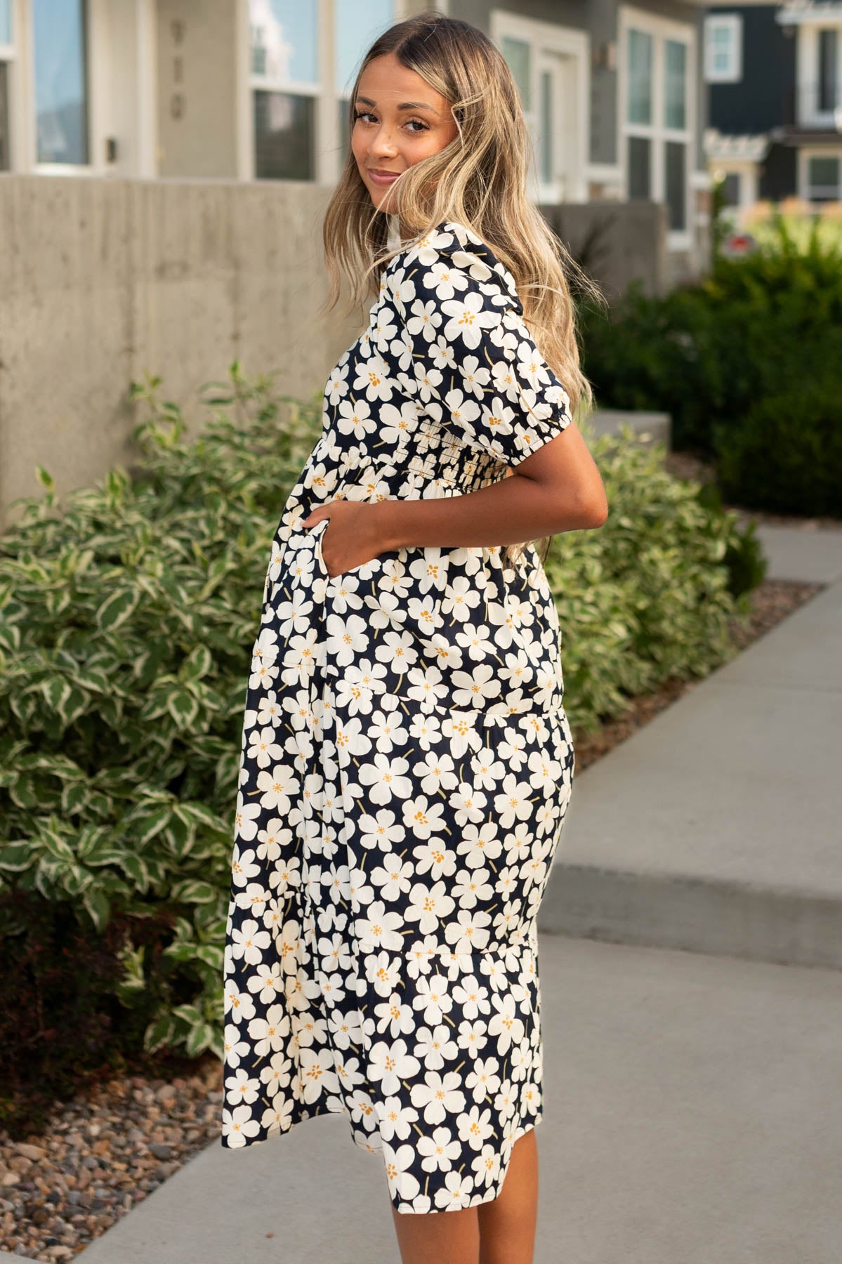 Side view of a ivory dress with a floral print and pockets