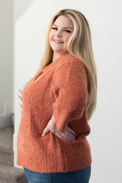 Side view of a plus size terracotta knit sweater