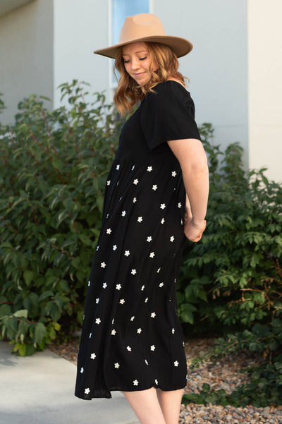 Side view of a black dress with small white flowers on the skirt