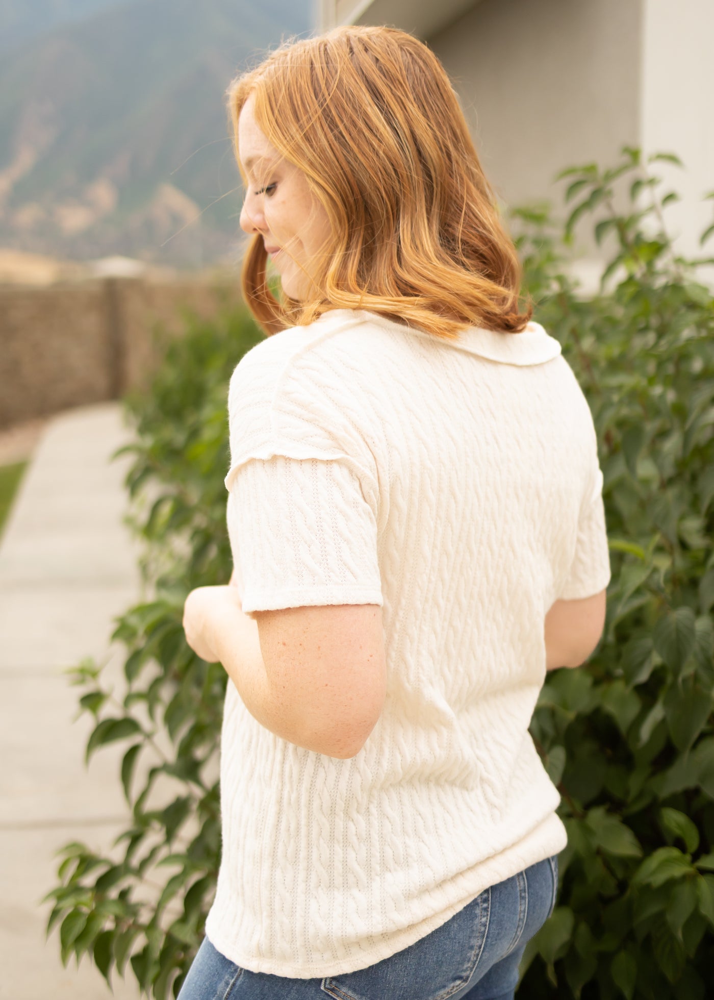 Side view of a short sleeve cream top with outside stitching