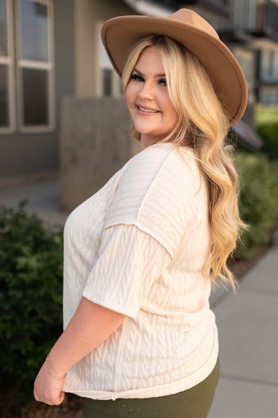 Side view of a plus size cream top