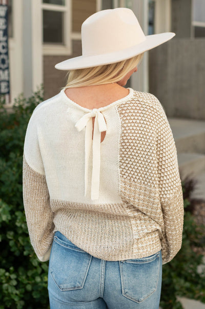 Back view with a tie at the neck of the taupe sweater