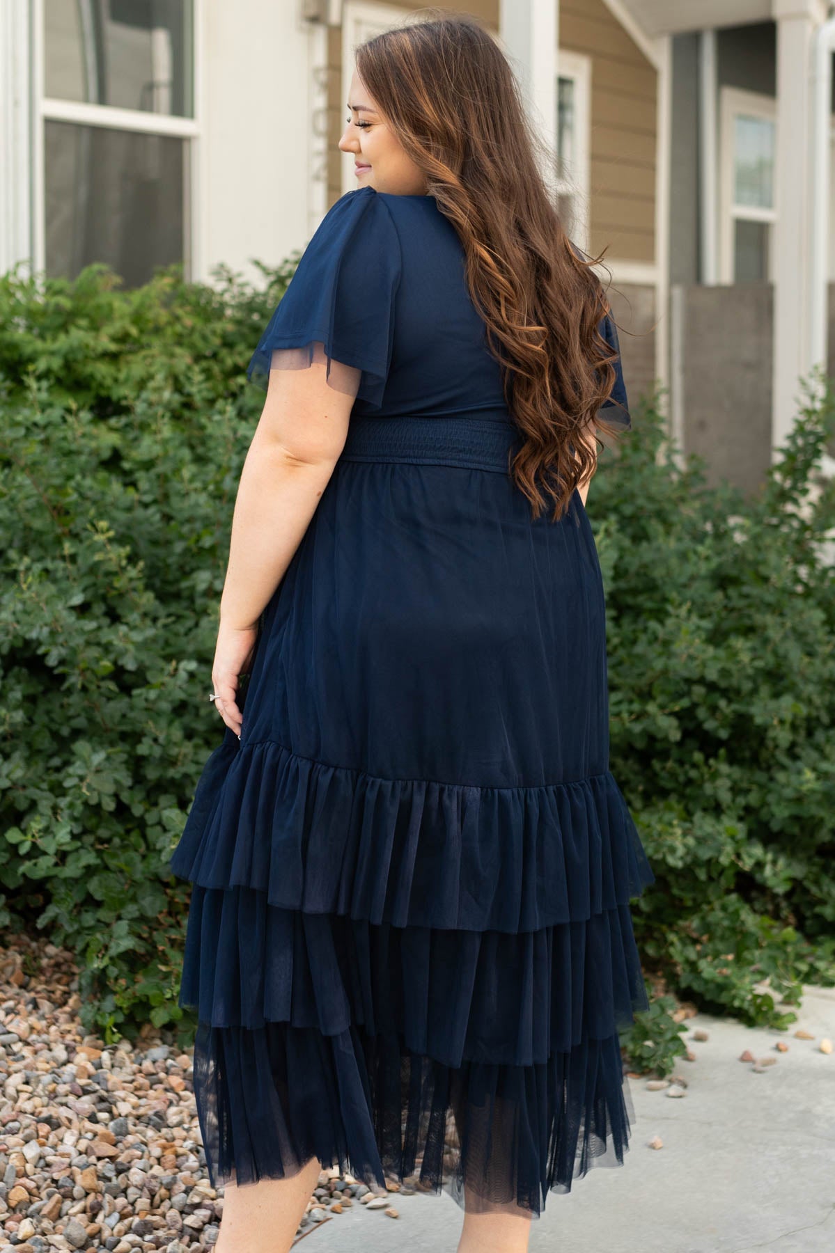 Plus size side view of a navy tiered dress