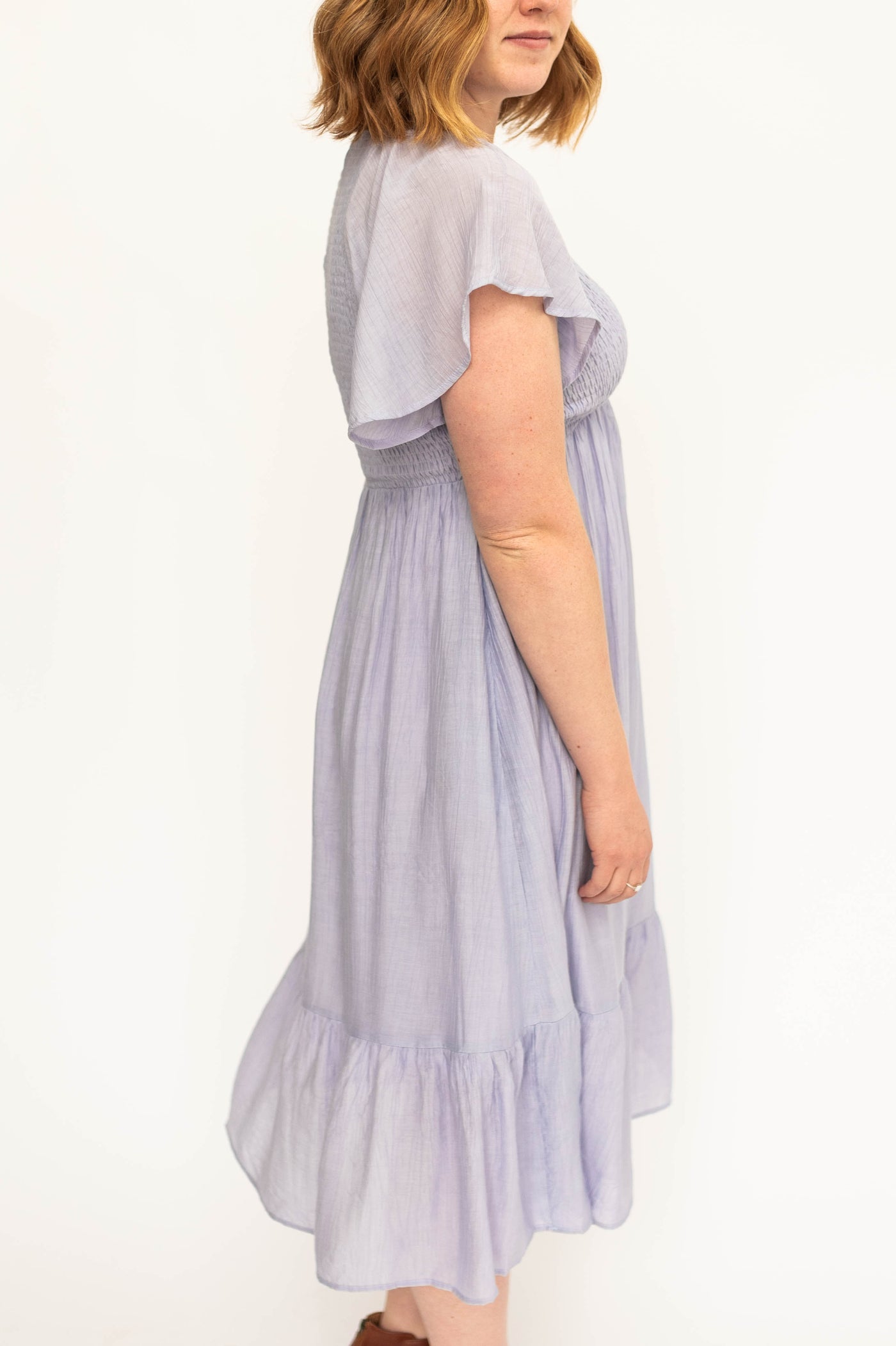Side view of a short sleeve Lavender satin dress with a V-neck and smocked bodice.