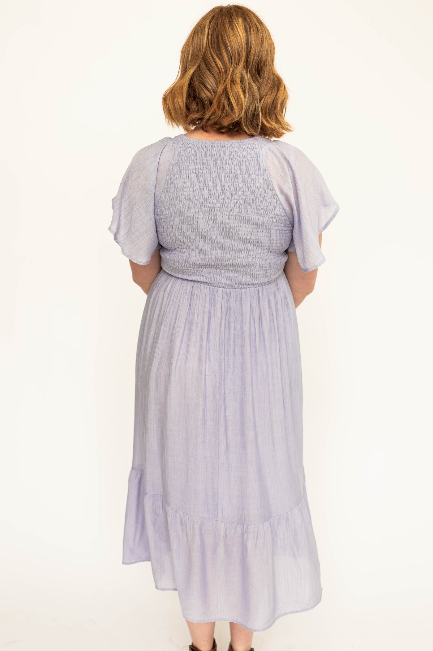 Back view of a Short sleeve lavender satin dress with a V-neck and smocked bodice.