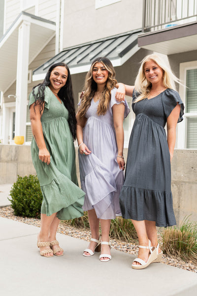 Dusty sage, lavender and denim blue satin calf length dresses, high waisted, short sleeve and smocked bodice.