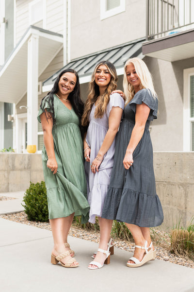 Dusty sage, lavender and denim blue satin calf length dresses, high waisted, short sleeve and smocked bodice.