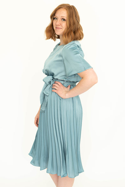 Side view of a french blue short sleeve satin dress with pleated skirt