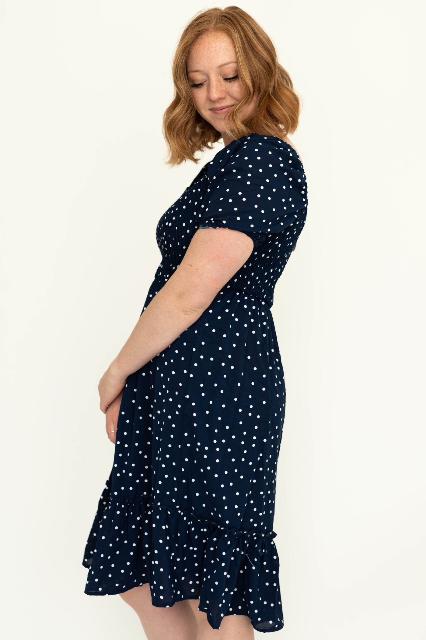 Side view of a navy dress with short sleeves, white dots and square neck