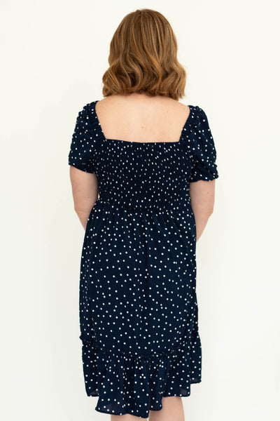 Back view of a navy dress with short sleeves, white dots and square neck