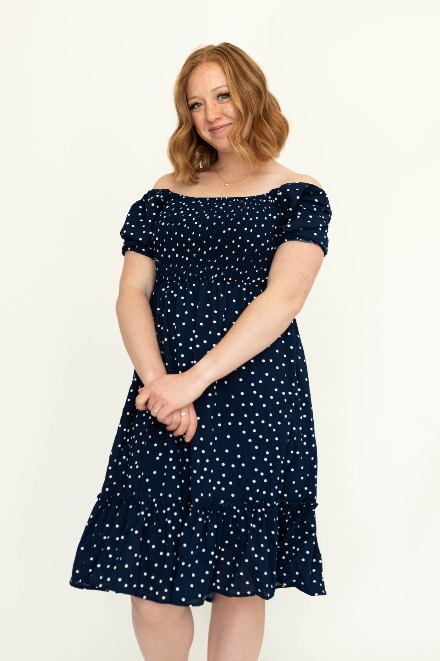 Front view of a navy dress with short sleeves, white dots and square neck