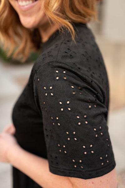 Close up on the fabric of a black eyelet dress