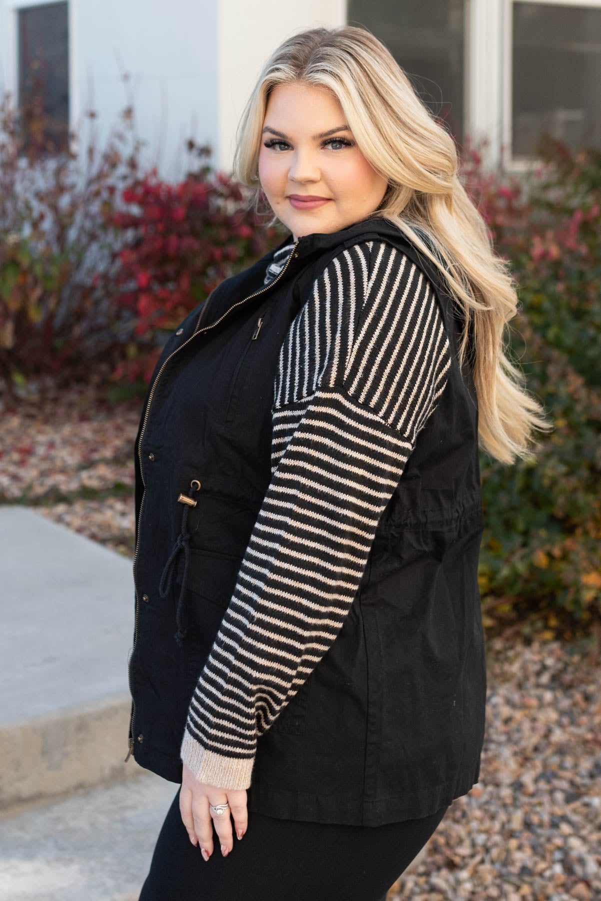 Side view of a plus size black hooded vest