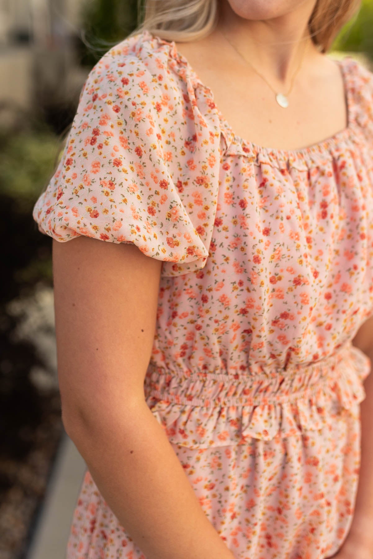 Close up view of the sleeve and neck line of a salmon floral dress