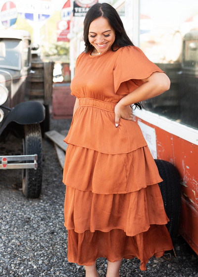 Side view of a short sleeve rust colored ruffle dress 