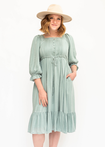 Seafoam green, 3/4 sleeve dress that ties at the waist and has a pleated bodice.