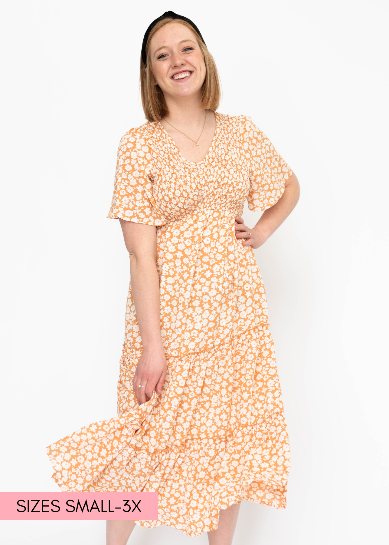 Short sleeve tiered apricot dress with white flowers and a V-neck.