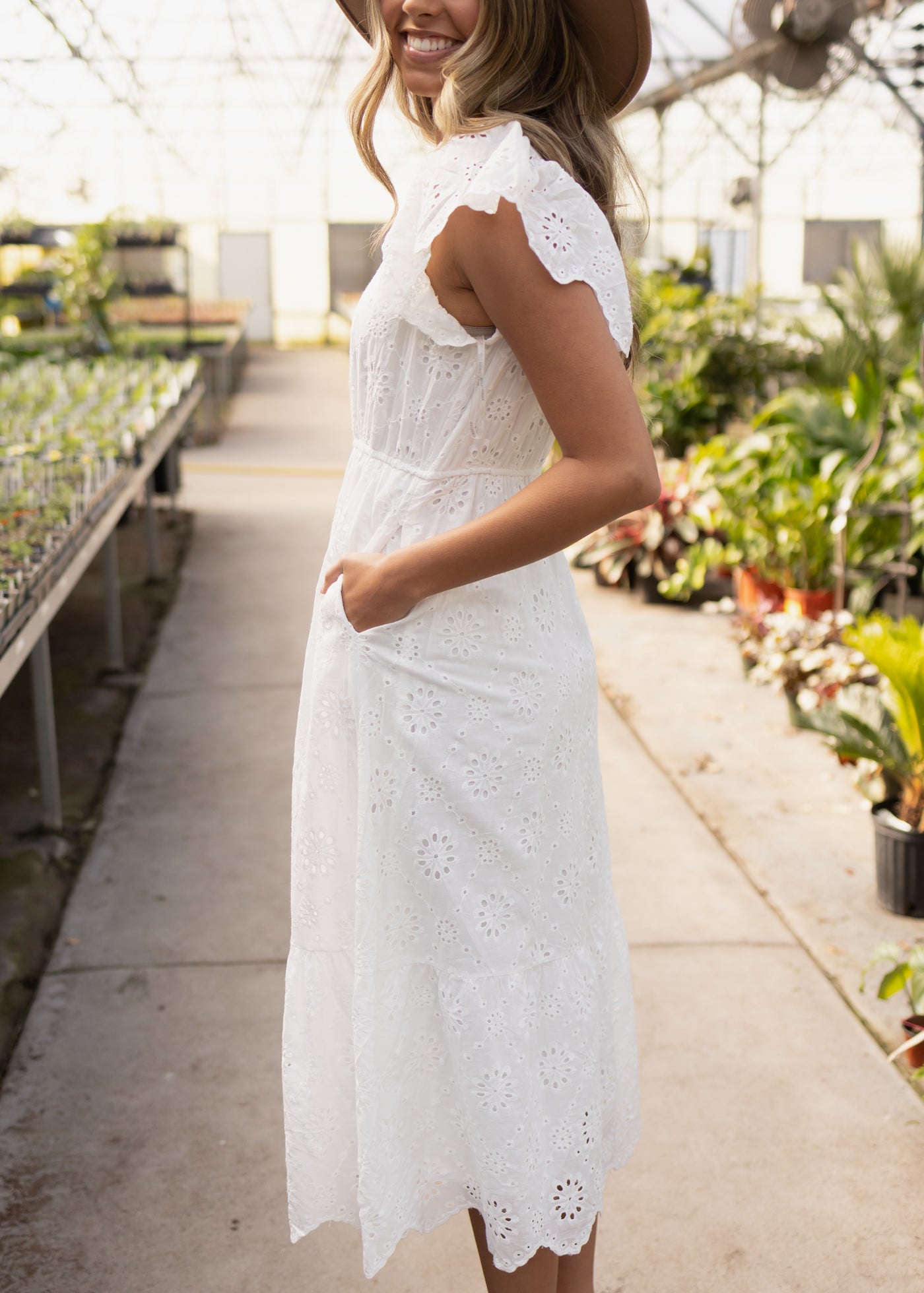 Side view of a white eyelet dress with pockets