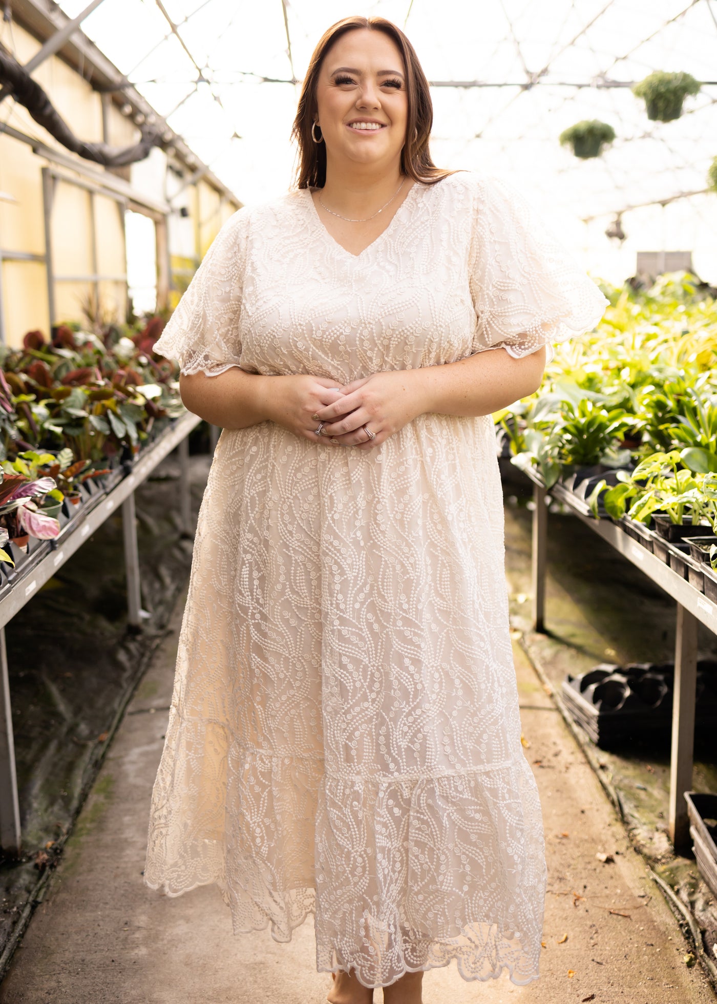 Front view of a plus size cream dress with scalloped hem