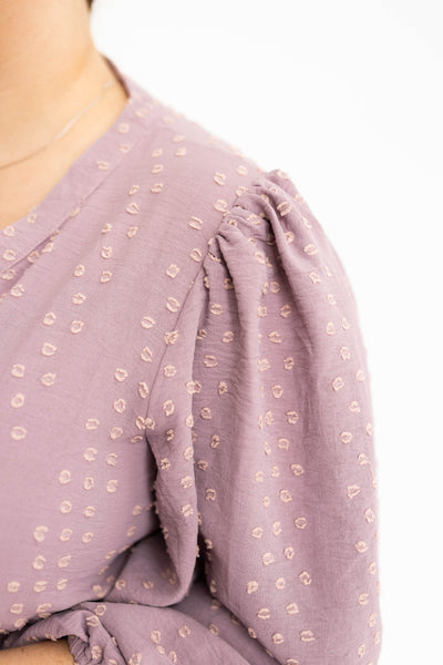 The sleeve of a lavender dress