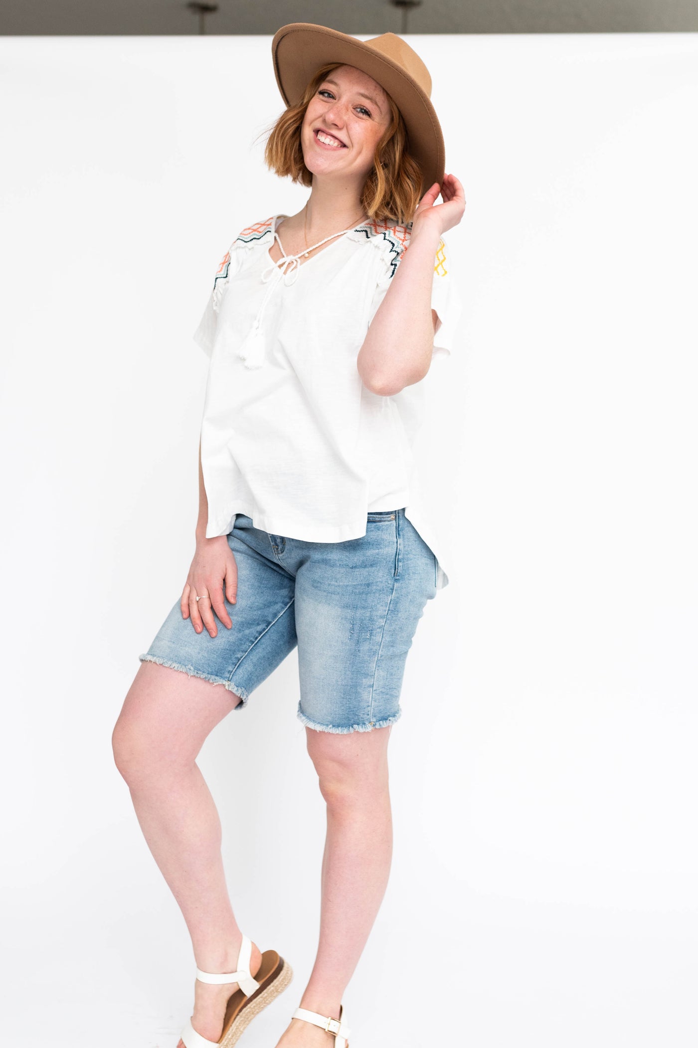 Short sleeve white top with a v-neck and pastel design on the shoulders
