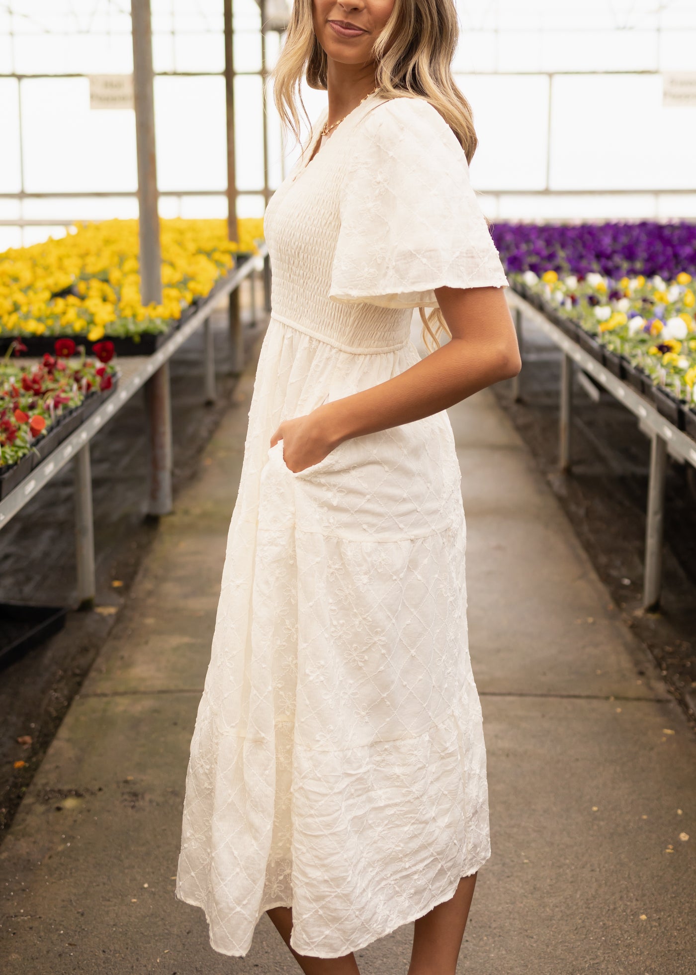 Side view of a short sleeve cream dress with pockets