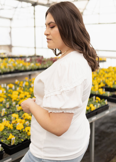 Side view of a white top with ruffle on the sleeves