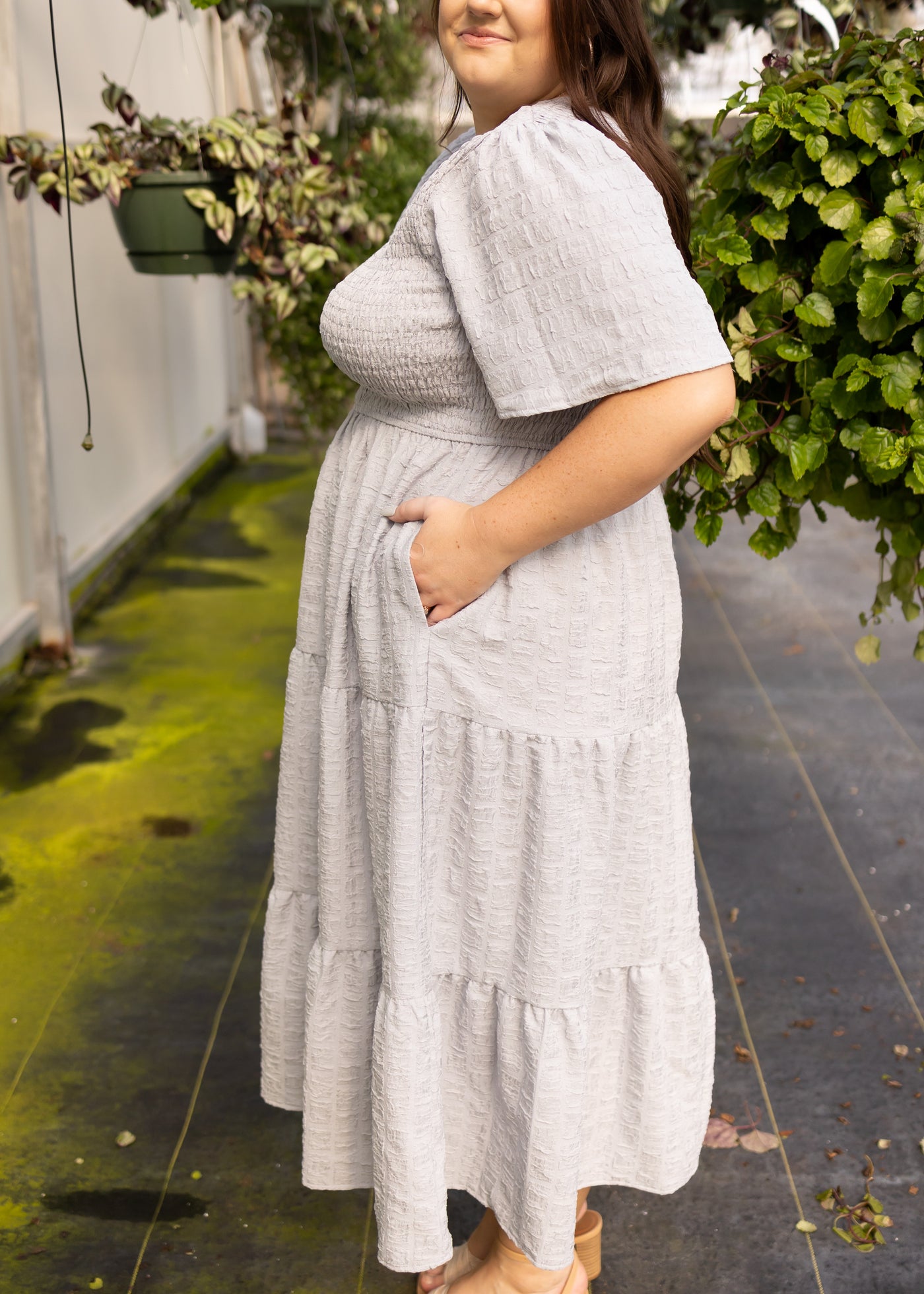 Side view of a plus size grey dress with pockets