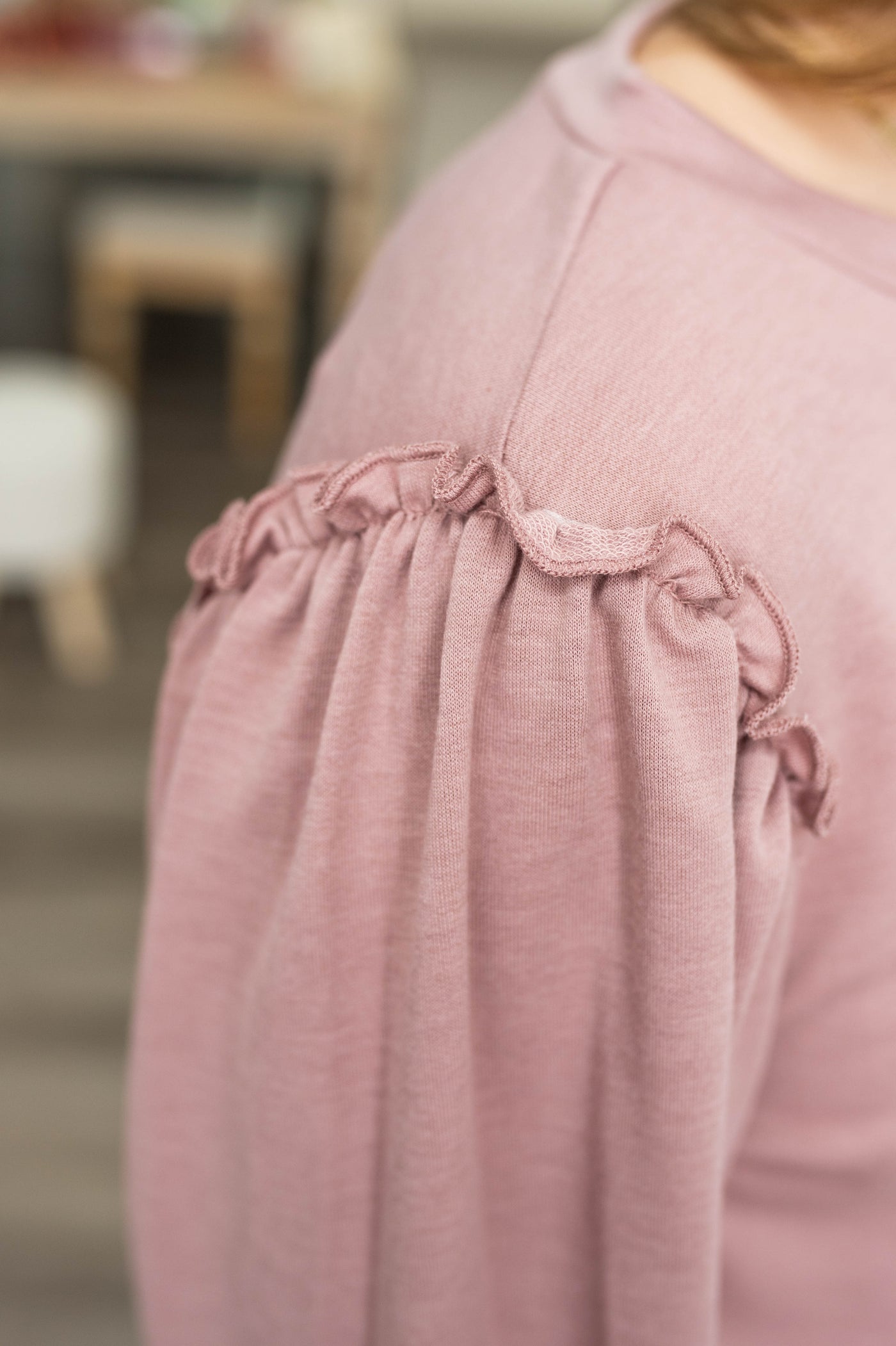 Close up of the ruffle on the shoulder of a mauve top