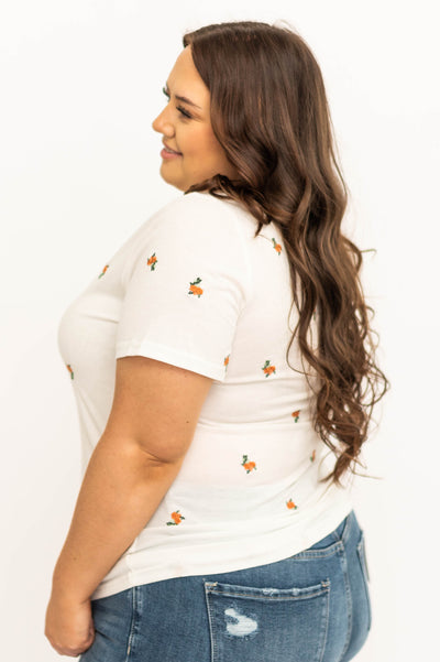 Side view of a plus size white top with coral flowers