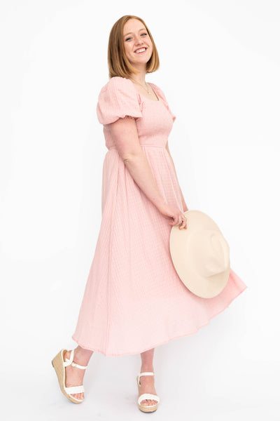 Side view of a mauve dress with pockets and smocked bodice
