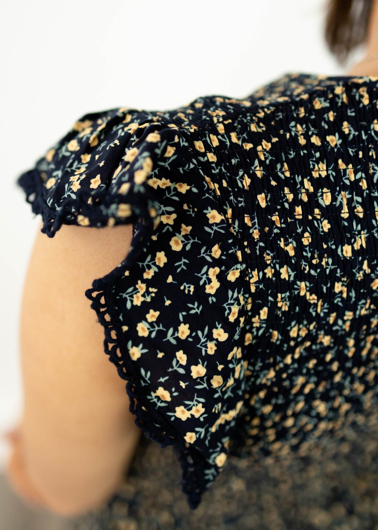 The sleeve of a navy floral dress